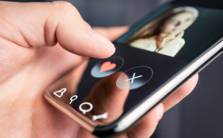 Un smart phone pe care sunt instalate aplicații de dating, ținut de într-o mână de bărbat