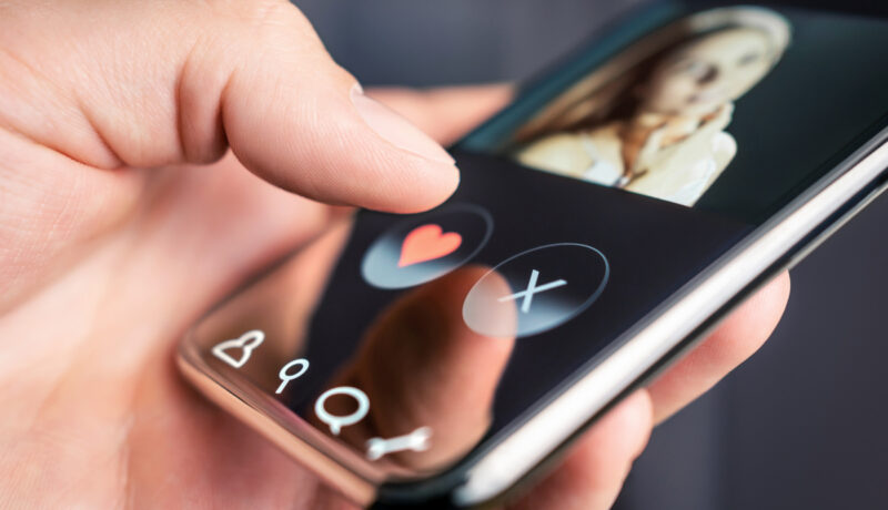Un smart phone pe care sunt instalate aplicații de dating, ținut de într-o mână de bărbat