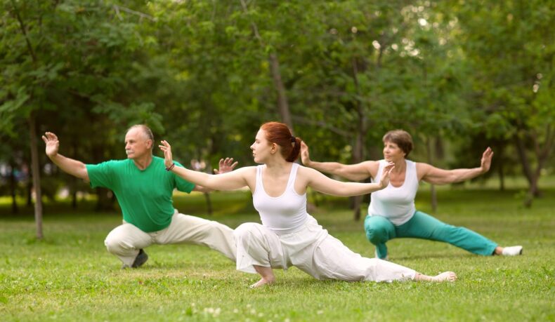 Grup de oameni care practică tahi chi într-un parc, un tip de exerciții pentru artrita reumatoidă