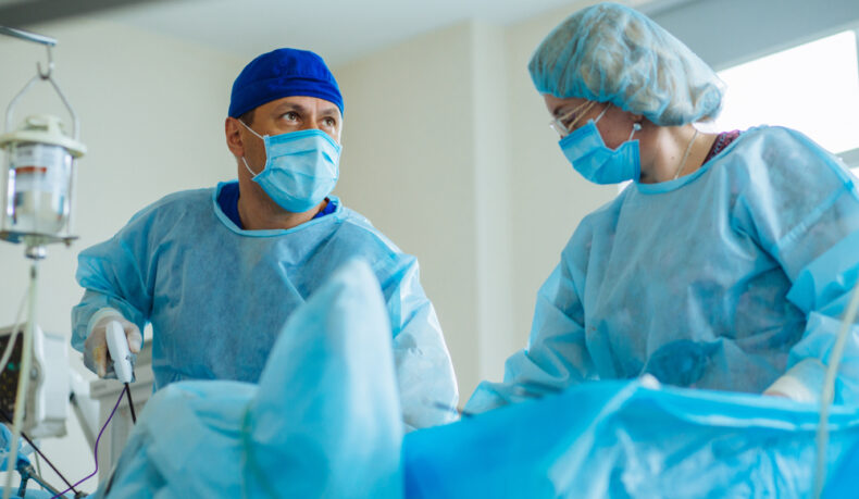 Un medic care operează și urmărește intervenția pe un ecran