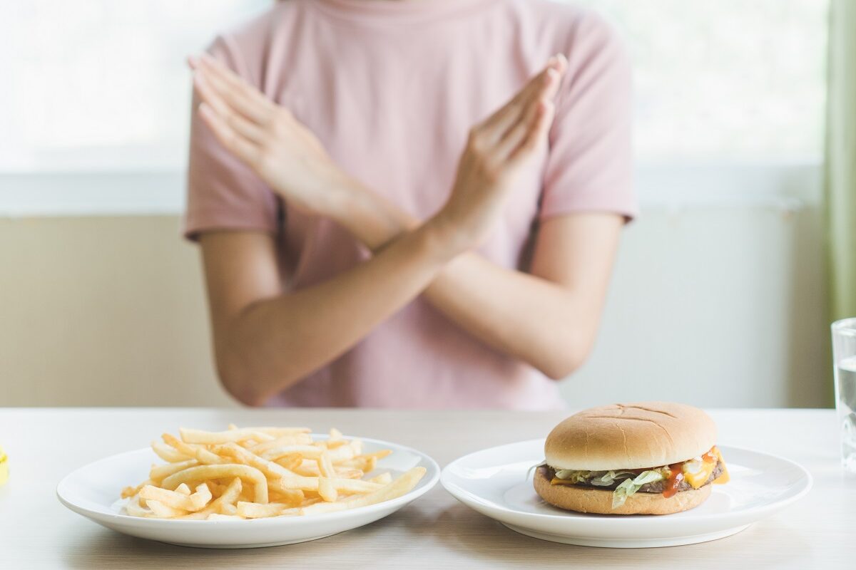 Femeie care refuză cartofi prăjiși și hamburger, aliemnte care trebuie excluse din dieta în artrită