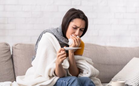 Femeie cu simptome de gripă verifică termometrul