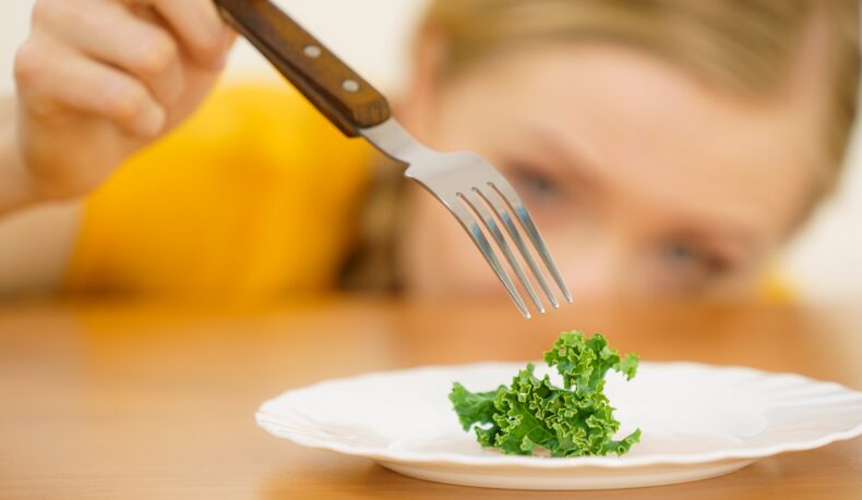 Femeie la dietă care mănâncă doar salată, sugestiv pentru alimentația dezordonată