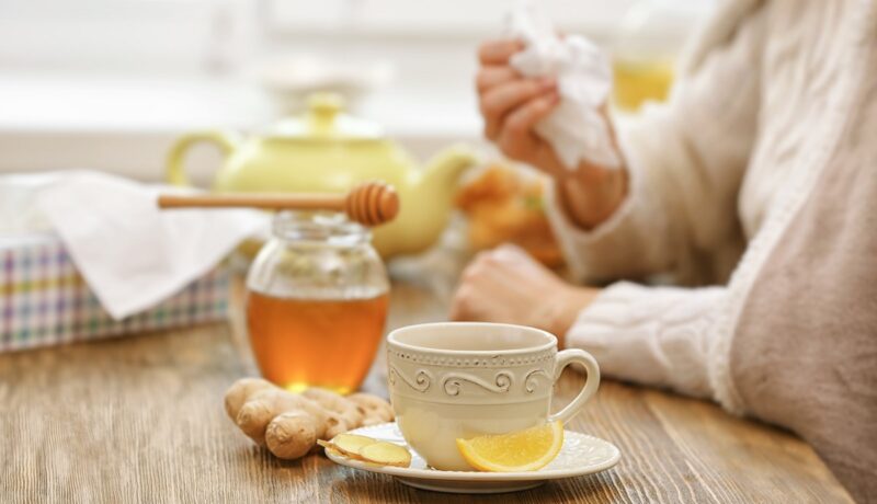 Femeie răcită care bea ceai de ghimbir, unul dintre cele mai indicate ceaiuri pentru răceală