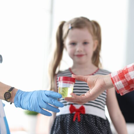 Probă de urină la medic și o fetiță fotografiată în fundal