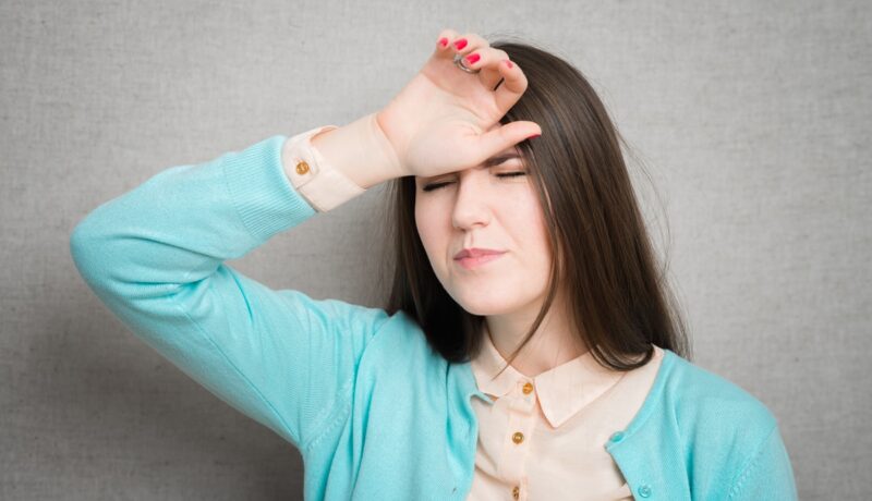 Femeie cu amețeli și durere de cap, simptome date de hipotensiunea arterială