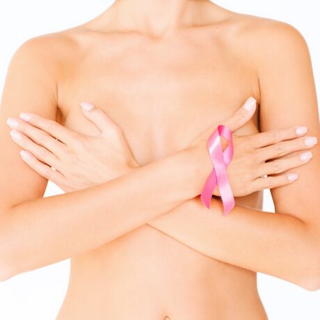 Femeie dezbrăcată, cu sânii acoperiți și o fundiță roz, simbolul pentru cancerul mamar
