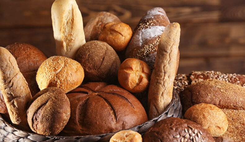 Mai multe tipuri de pâine, într-un coș, pe o masă