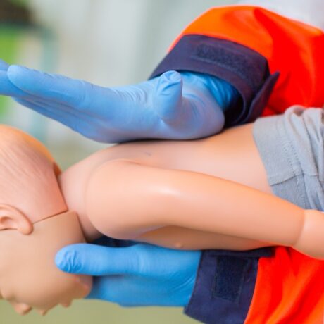 Paramedic care acordă unui bebeluș de jucărie primul ajutor în caz de înec cu lapte sau mâncare