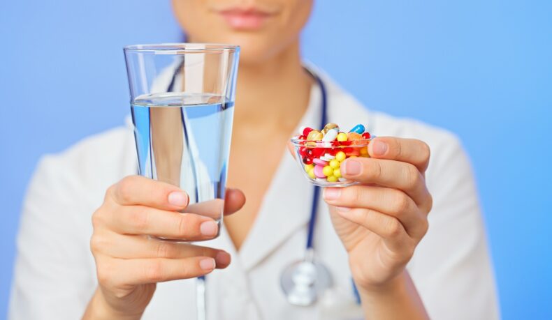 Medic care oferă antibiotice și un pahar cu apă