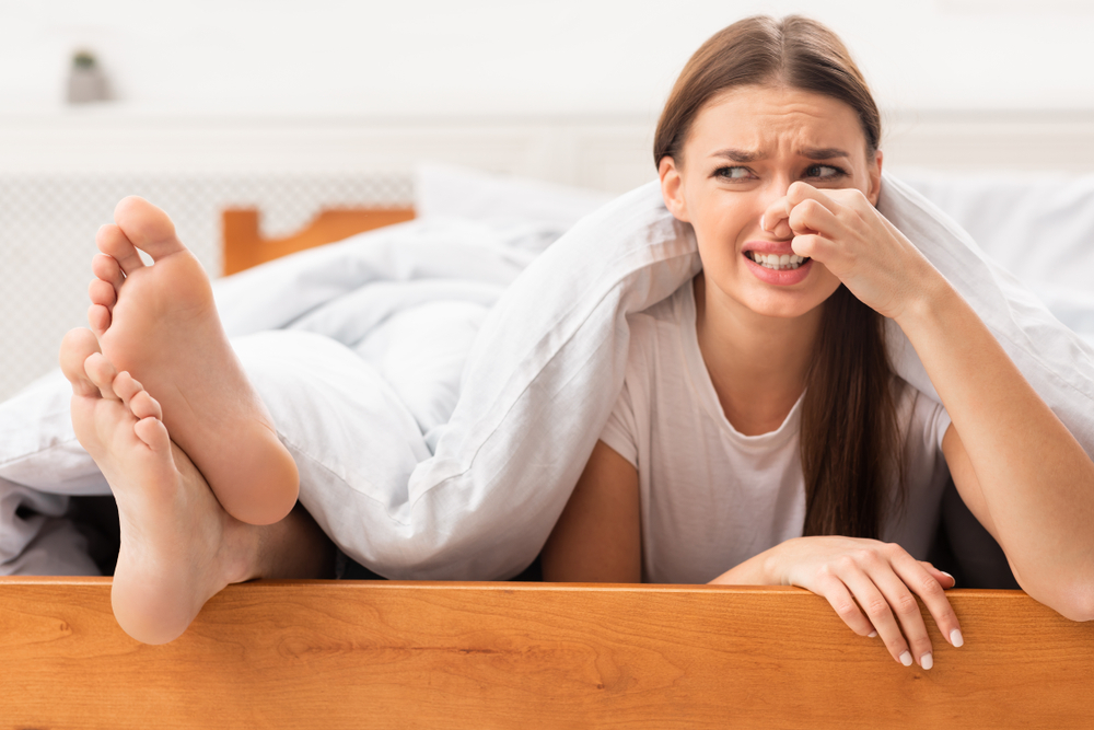 O femeie care se ține de nas din cauza mirosului urât al picioarelor partenerului