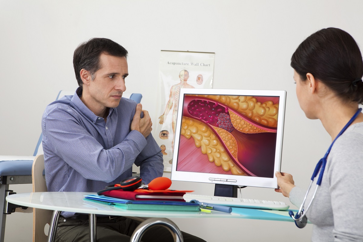 Bărbat la medic căruia i se arată ce efecte are un colesterol mărit asupra vaselor de sânge și cum se depune pe artere