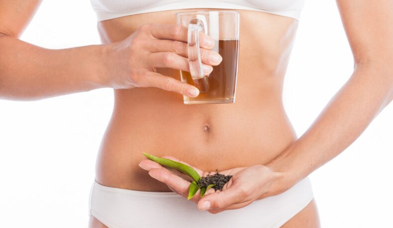 Femeie cu o ceașcă de ceai și frunze de ceai uede, unul dintre cele mai eficiente ceaiuri pentru constipație