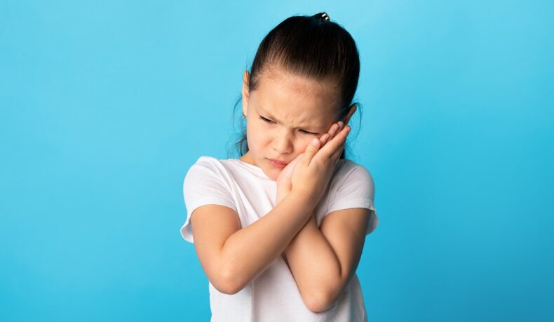 Fetiță cu durere de obraz, unul dintre simptomele pe care le are oreionul