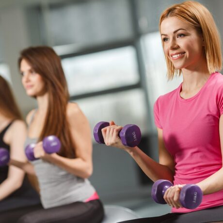 Femeie care face exerciții cu greutăți. Ele pot fi combinate cu antrenamentele cardio