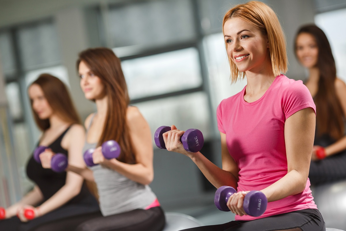 Femeie care face exerciții cu greutăți. Ele pot fi combinate cu antrenamentele cardio