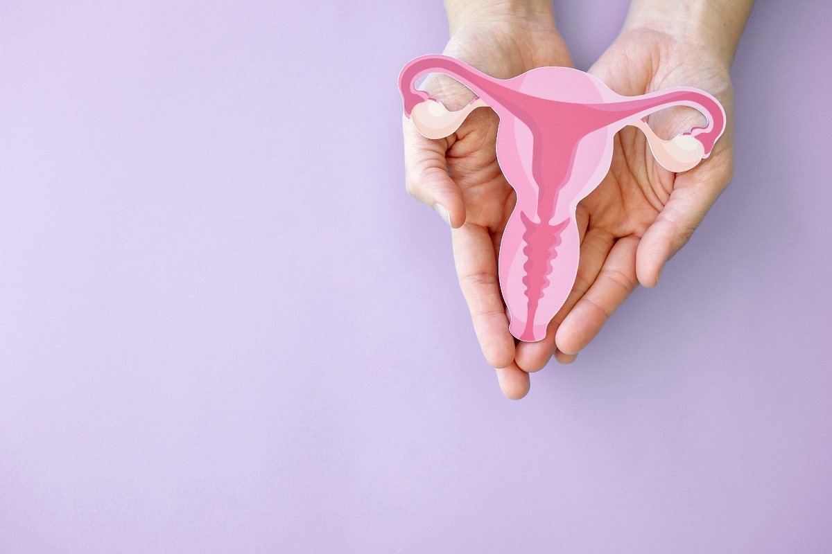 Femeie cu aparatul reproducător feminin în palme, sugestiv pentru cancerul de col uterin
