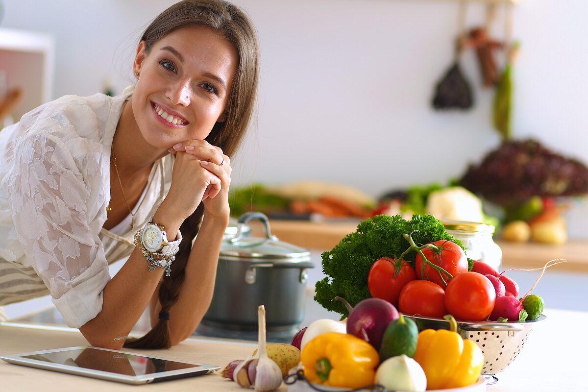 Femeie cu legume colorate pe masă, care sunt pe lista celor mai recomandate alimente care scad rezistența la insulină
