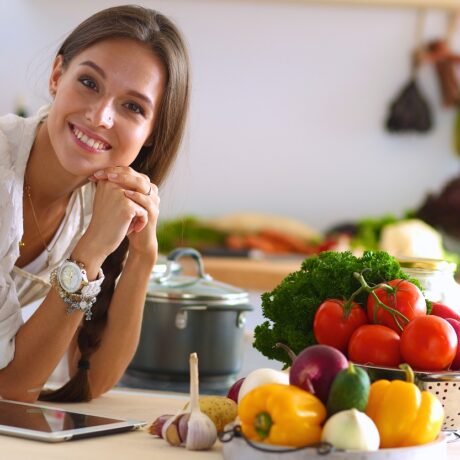 Femeie cu legume colorate pe masă, care sunt pe lista celor mai recomandate alimente care scad rezistența la insulină