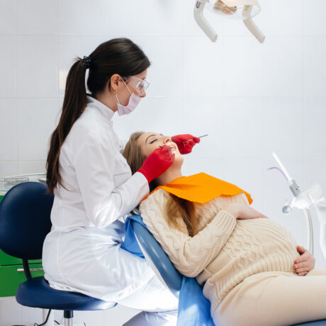 O femeie care se află în cabinetul medicului stomatolog în timp ce medicul îi repară dinții