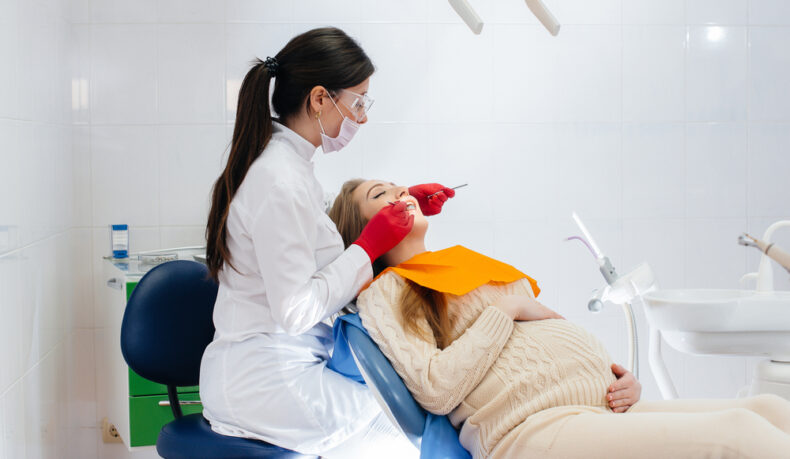 O femeie care se află în cabinetul medicului stomatolog în timp ce medicul îi repară dinții