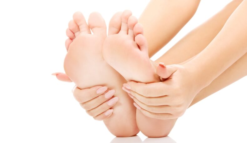 Femeie care își analizează picioarele. Semnele unui colesterol crescut sunt vizibile în sănătatea picioarelor.