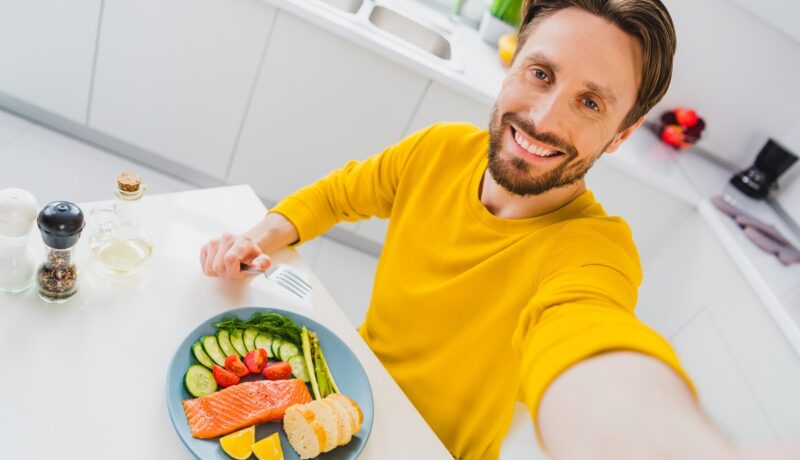 Bărbat cu farfurie de pește și legume în față, unele dintre cele mai recomandate alimente care previn blocarea arterelor