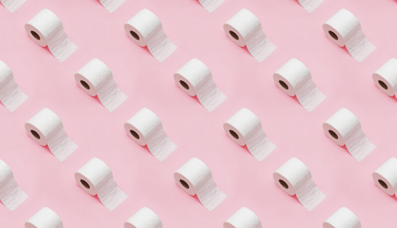 Mai multe role de hârtie igienică desfăcute, fotografiate pe un fundal roz