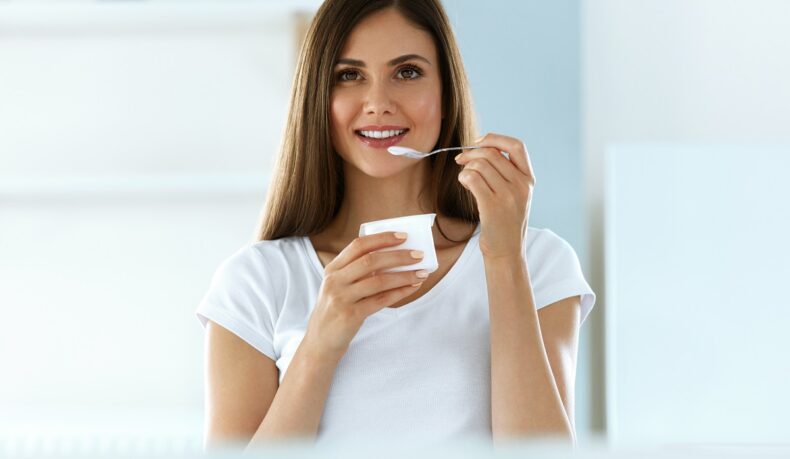 Femeie care mănâncă iaurt, unul dintre alimentele bogate în probiotice