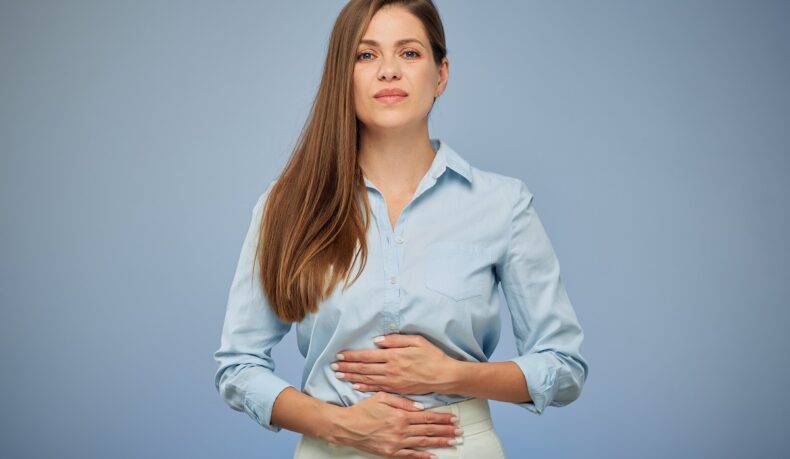 Femeie cu durere de stomac, unul dintre simptomele Helicobacter pylori.