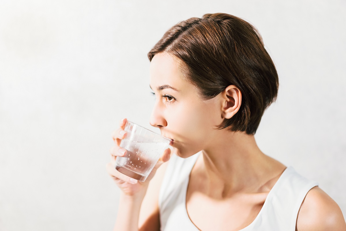 Femeie care bea apă carbogazoasă dintr-un pahar