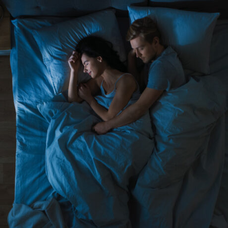 O femeie și un bărbat care dorm într-un pat matrimonial