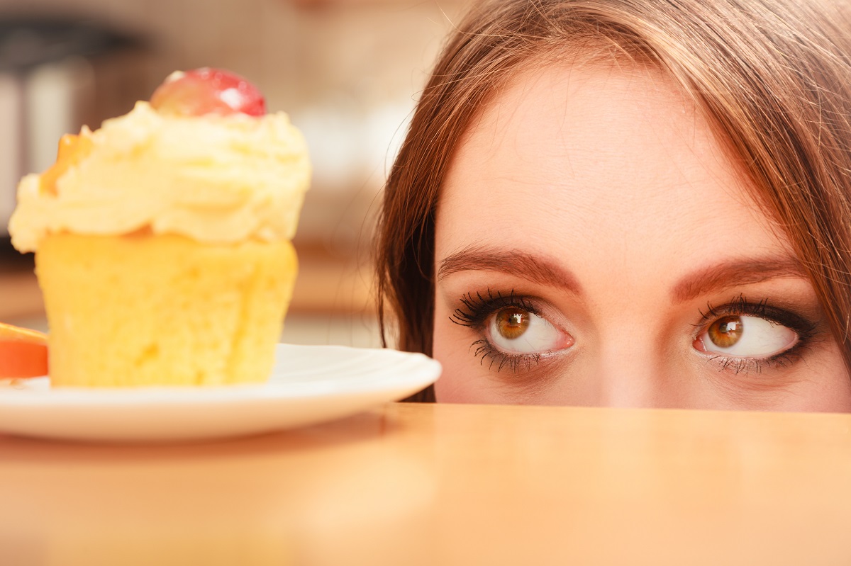 Femeie care privește o prăjitură, sugestiv pentru pofta de dulce