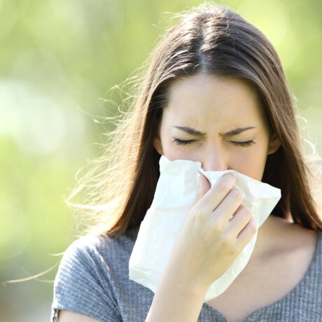 Femeie cu alergie care își suflă nasul, sugestiv pentru alergiile respiratorii
