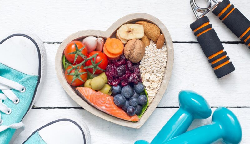 Alimente sănătoase pe un platou, teniși și gantere, sugestiv pentru metodele care ajută la controlul diabetului