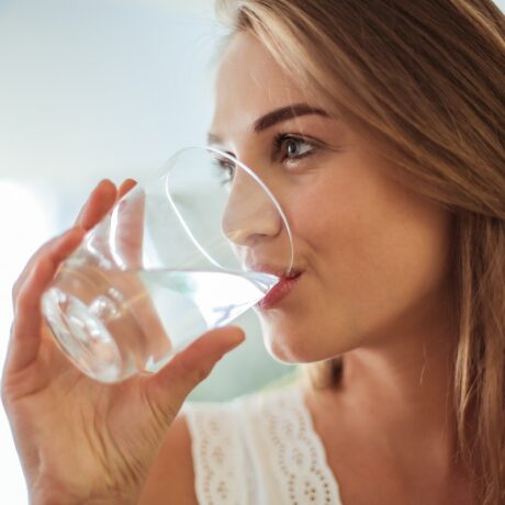 Femeie care bea un pahar cu apă