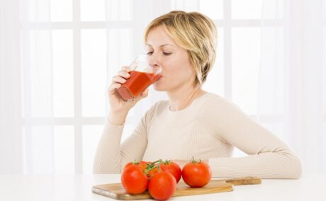 Femeie care bea suc de roșii, care se află pe lista de băuturi care scad glicemia