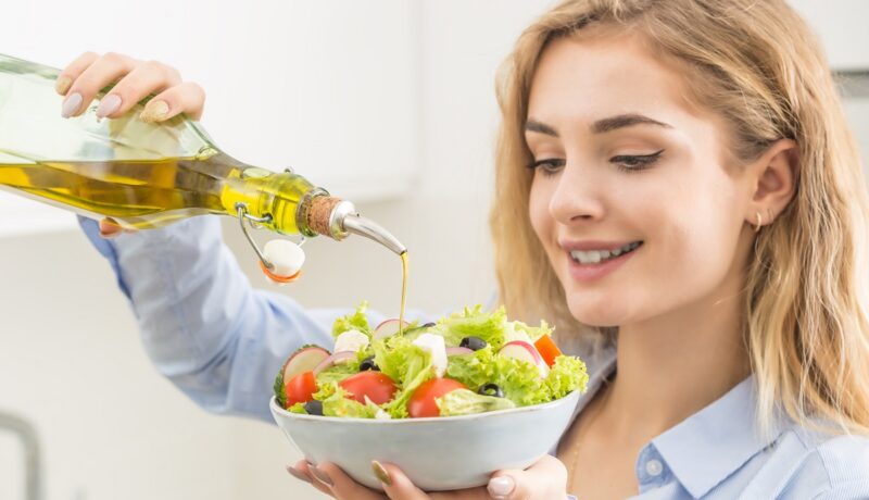 Femeie care prepară o salată cu ulei de măsline, recomandată la începutul mesei, conform unei reguli de alimentație