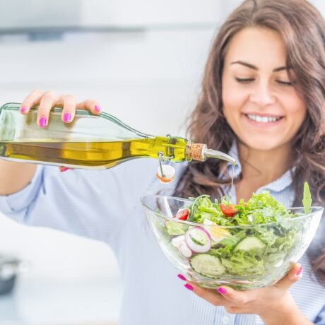 Femeie care toarnă ulei de măslne extravirgin într-o salată