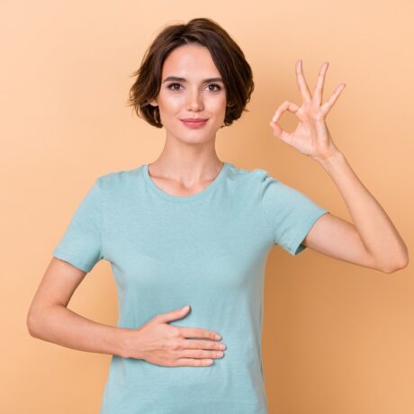 Femeie cu mâna pe burtă care arată semnul OK, sugestiv pentru digestie ușoară și corectă