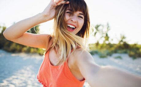 O femeie tânără râde și se fotografiază
