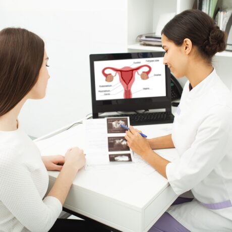 Medic ginecolog care îi explică unei paciente despre aparatul reproducător pe o ecografie și imagine, sugestiv pentru rezerva ovariană