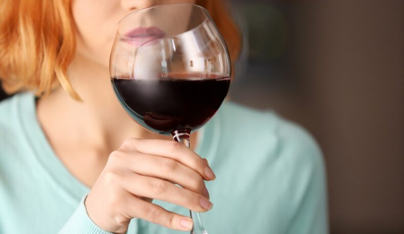 femeie care bea un pahar de vin roșu