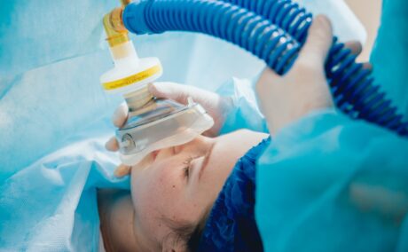 Femeie în spital care a primit anestezie totală și i se pune mască de oxigen, sugestiv pentru efectele adverse ale anesteziei