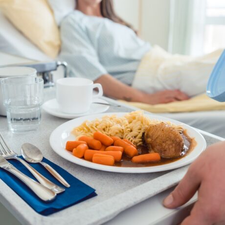 Femeie în spital care primește mâncare la pat, sugestiv pentru regimul alimentar după operație