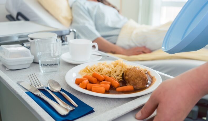 Femeie în spital care primește mâncare la pat, sugestiv pentru regimul alimentar după operație