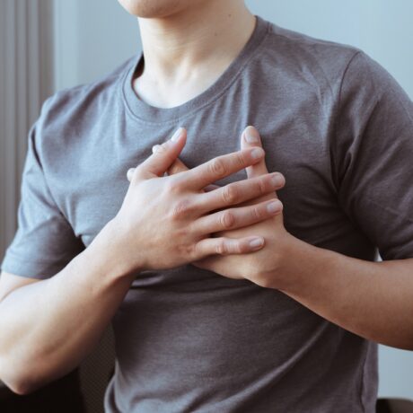 Bărbat care se ține cu mâinile de piept, sugestiv pentru durerea în piept, nul dintre cele mai comune semne care prevestesc infarctul