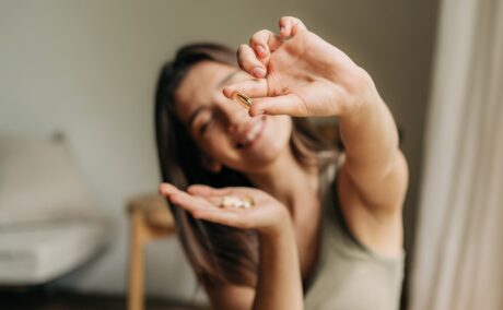 Femeie care arată o pastilă și ține în mână vitamine pentru energie