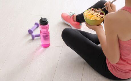 Femeie care mănâncă un bol cu fructe și cereale înainte sau după fitness