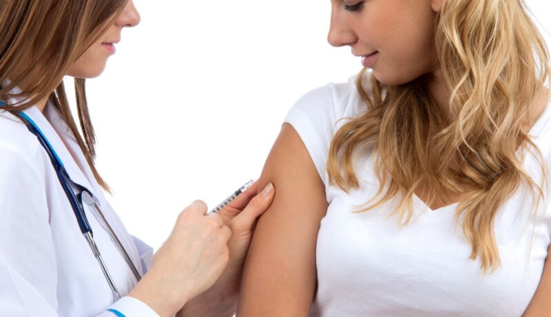 Medic care vaccinează o femeie în braț, sugestiv pentru vaccinul antigripal în sezonul 2023-2024